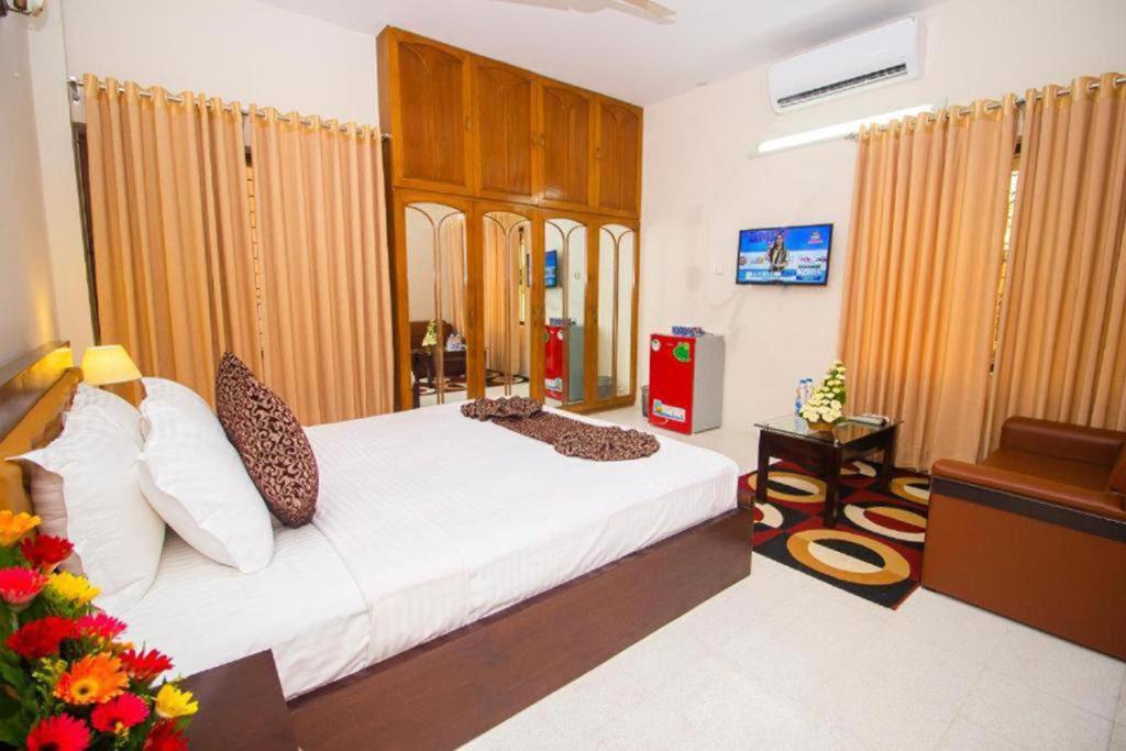 a bedroom with a large bed and a couch at Suite Palace in Dhaka
