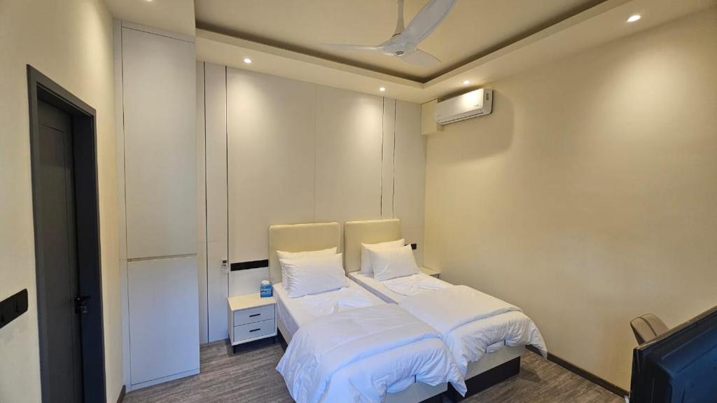 un dormitorio con una cama con sábanas y almohadas blancas en Oceara Dharavandhoo, en Dharavandhoo