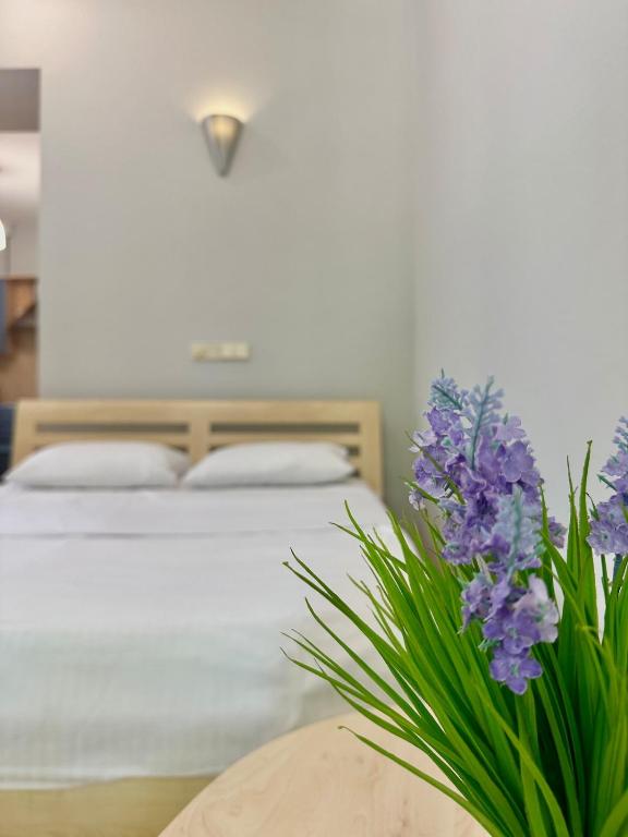 a bedroom with a bed and a table with purple flowers at 1 room right near the Kreschatyk in Kyiv