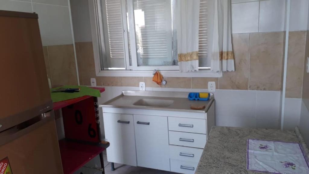 een kleine keuken met een wastafel en een raam bij Residencial Roma AP01 in Capão da Canoa