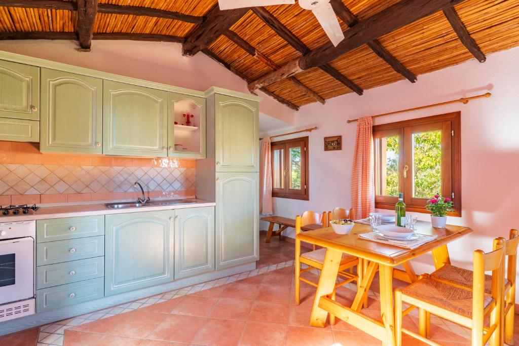 eine Küche mit grünen Schränken und einem Holztisch in der Unterkunft Appartamenti Tiffany in San Teodoro