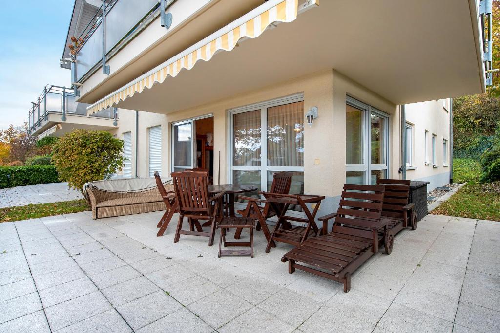 a patio with wooden chairs and a table and benches at Ferienwohnung Baier in Überlingen