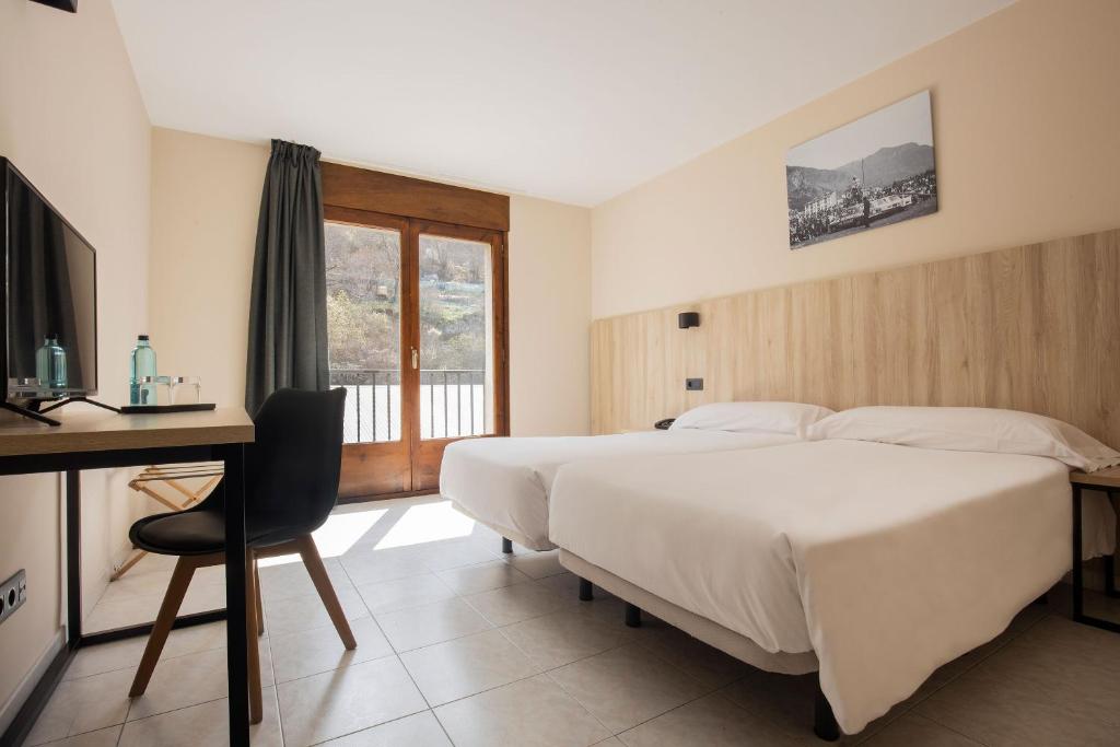 a bedroom with a bed and a desk and a television at Hotel Encamp by Nexta in Encamp