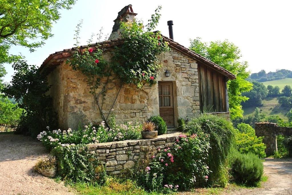 an old stone house with flowers in front of it at Mas del Lum in Boussac