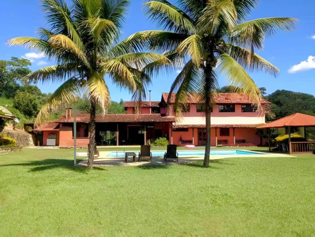 een huis met twee palmbomen ervoor bij Haras Santa Amalia - Nova União MG in União de Caeté