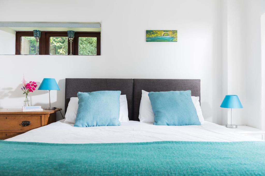 a bedroom with a large bed with blue pillows at Lower Marsh Farm B&B in Saltash