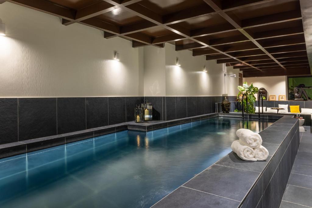 a swimming pool in a building with a pool at Hôtel & SPA Le Chêne Vert in Brive-la-Gaillarde