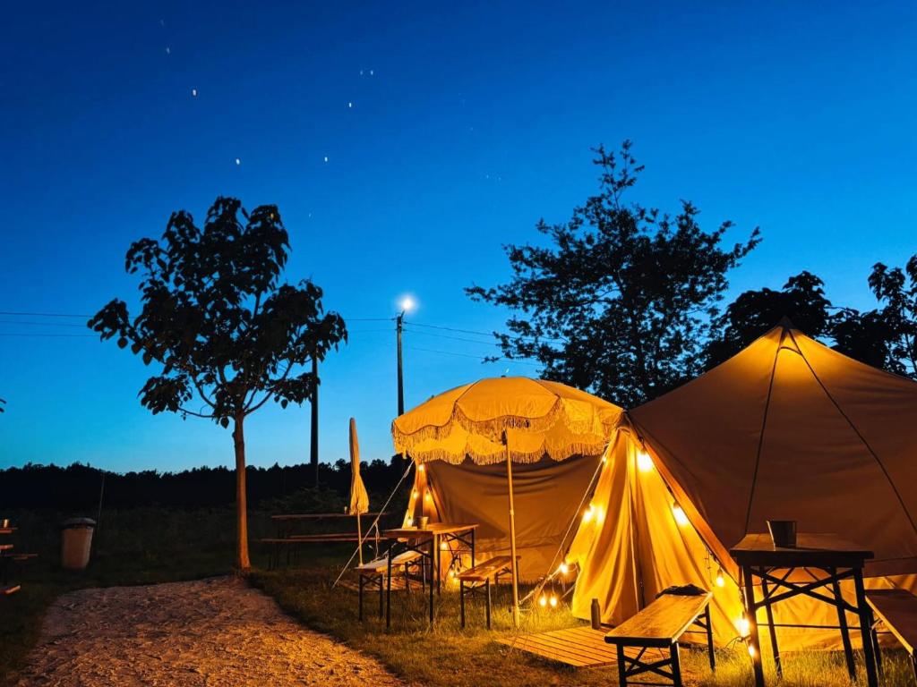 Dos tiendas de campaña con sillas y una mesa por la noche. en O Pedrouzo Base Camp, en O Pino 
