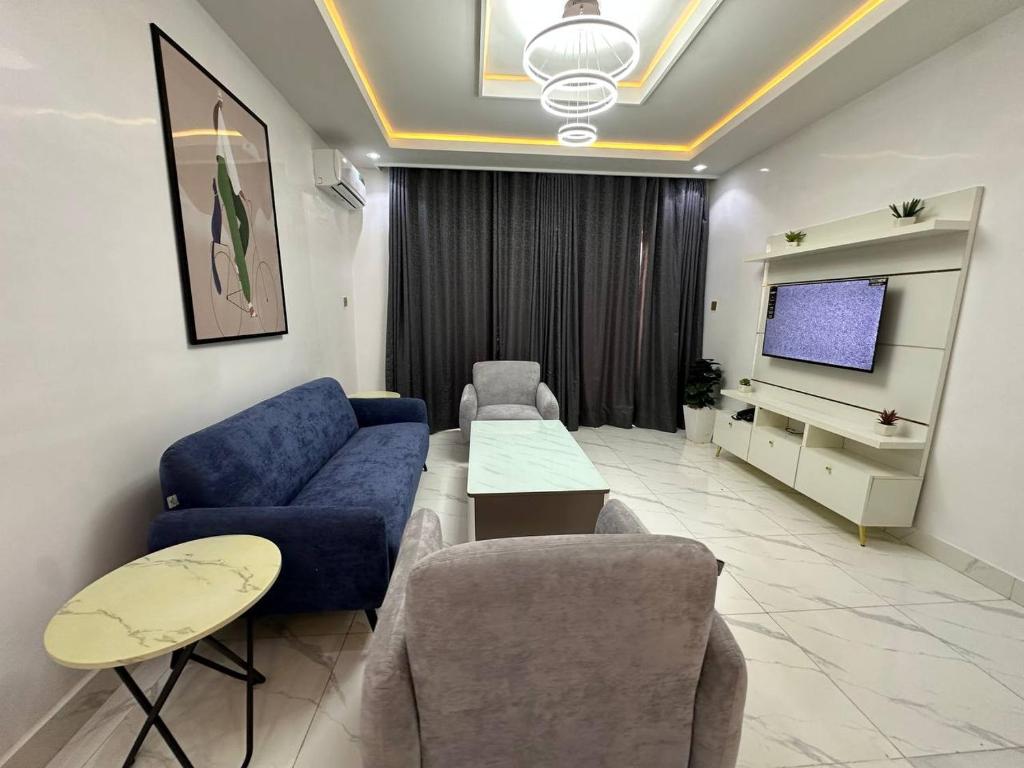 een woonkamer met een blauwe bank en een tv bij Prestine Apartments in Abuja