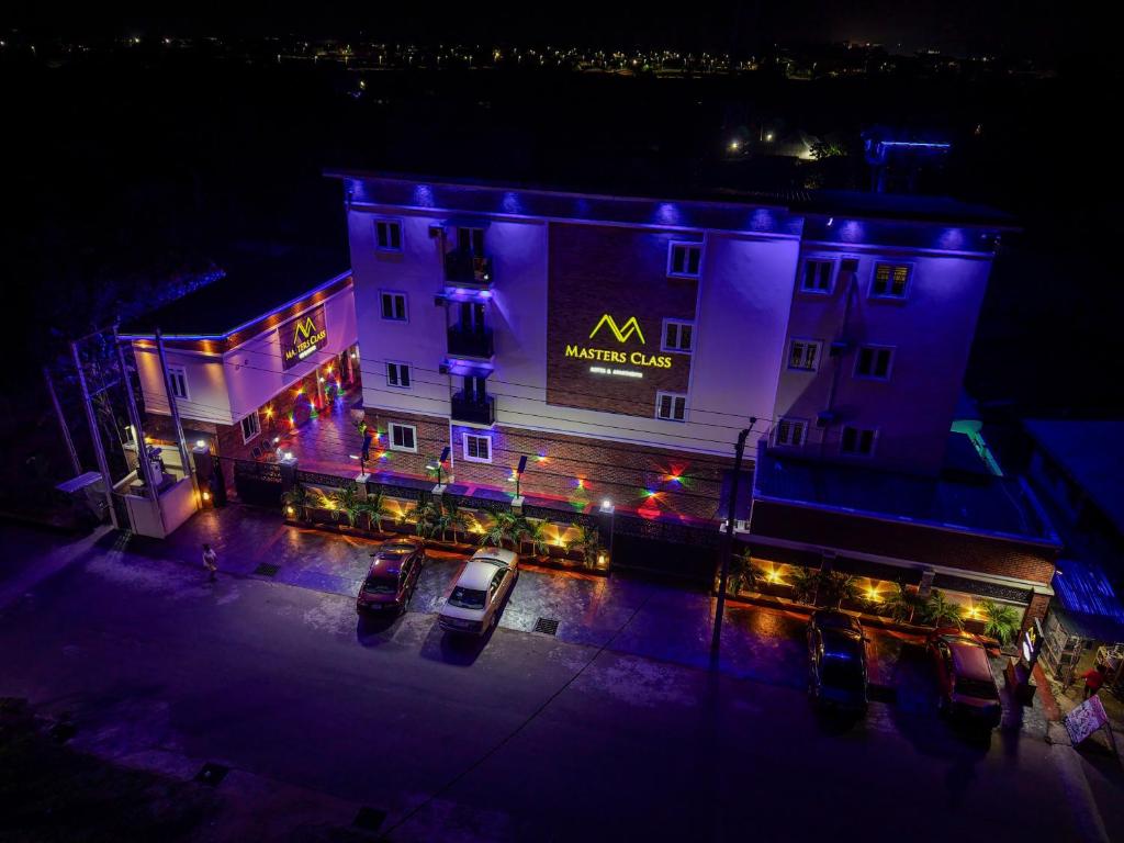 a large building with a sign on it at night at Masters Class Apartments in Mama