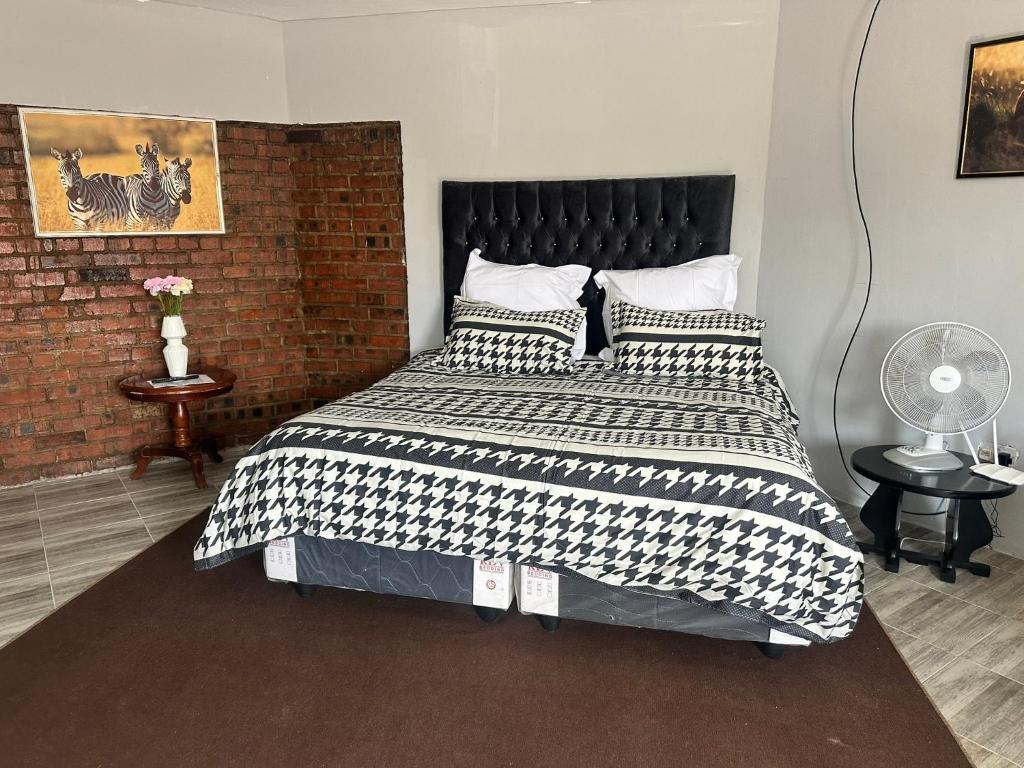 a bedroom with a large bed with a brick wall at Staylax guesthouse in Harare