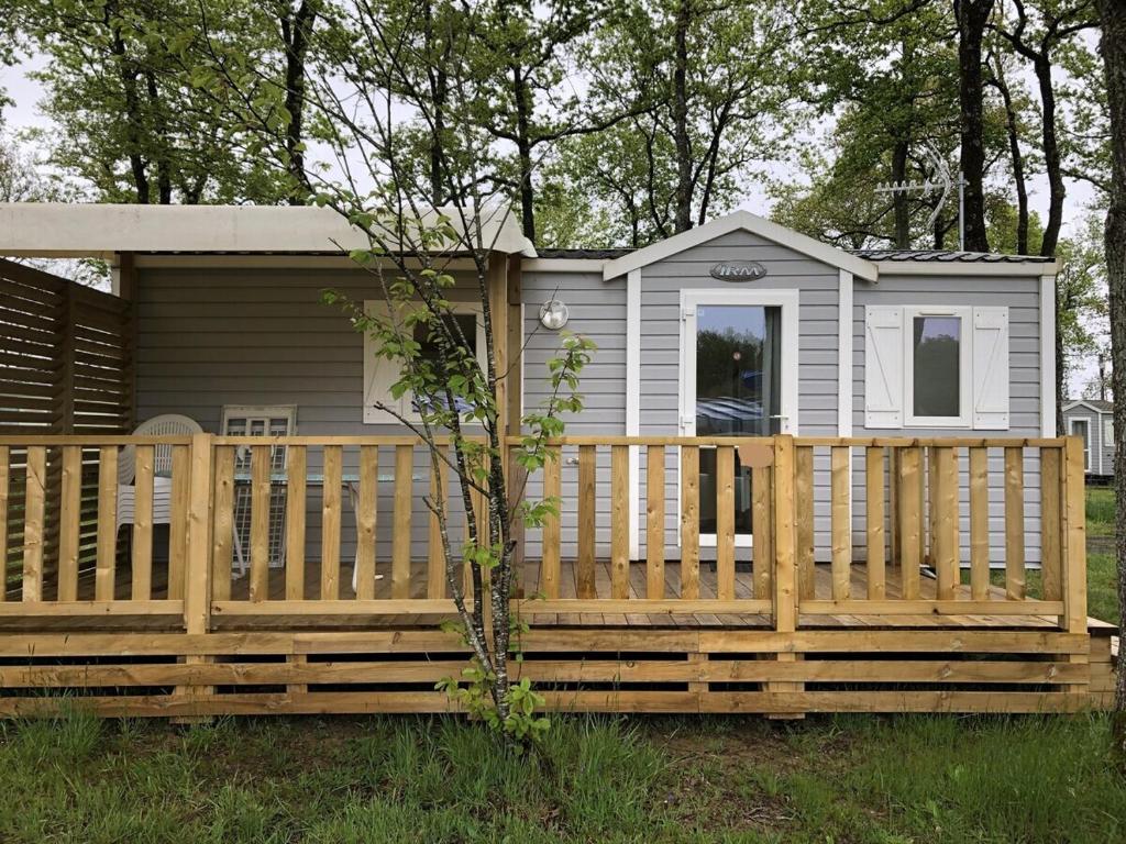 a tiny house with a wooden fence in front of it at Bungalow "CONFORT" PUY duFOU 2CH-5pers 720FA in La Boissière-de-Montaigu