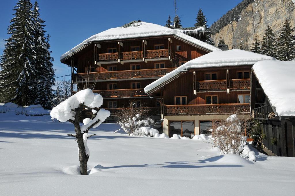 モルジヌにあるHotel Les Lansの雪が積もった大きな木造建築