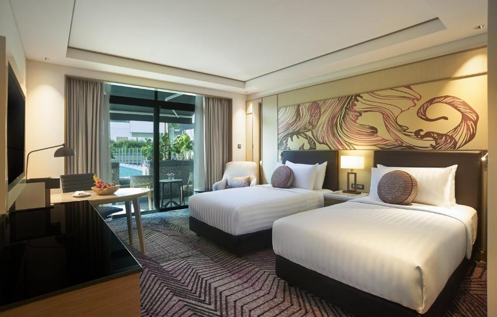 een hotelkamer met twee bedden en een bureau bij Amari Johor Bahru in Johor Bahru