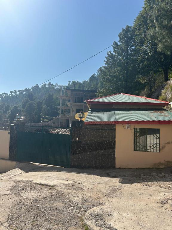 a building with a green roof and a fence at Aqua pura Lodges By Ansar Qureshi in Murree