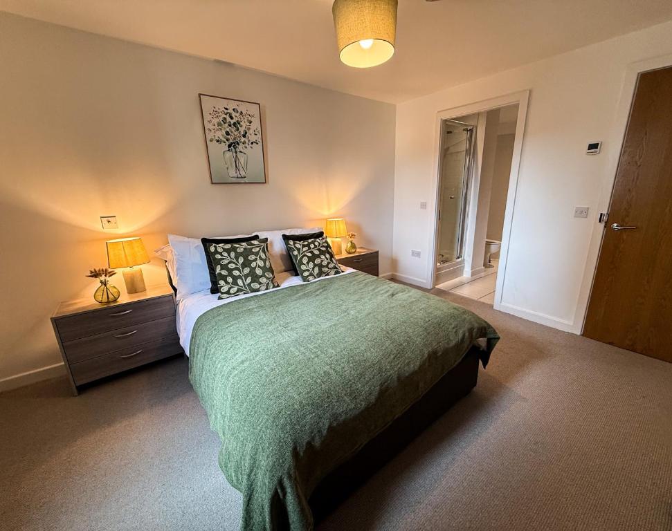 a bedroom with a bed with a green blanket and two lamps at Spacious City Centre 2 Bedroom Apartment in Liverpool