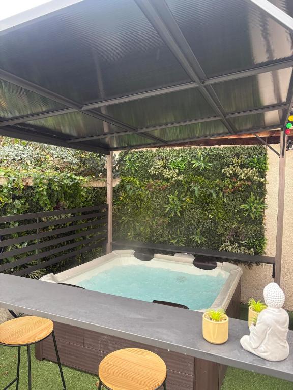 een hottub onder een luifel met twee stoelen en een tafel bij Zen Room SPA luxe in Roanne