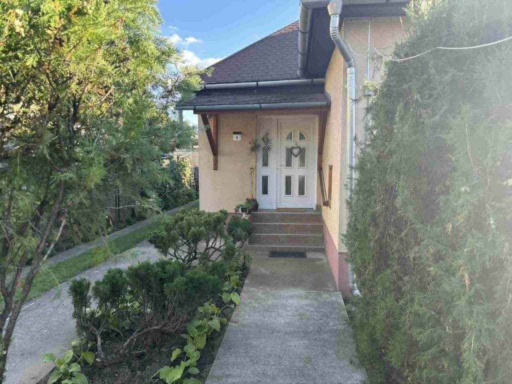 uma casa com uma porta branca e algumas árvores em Kitti Kuckója em Debrecen