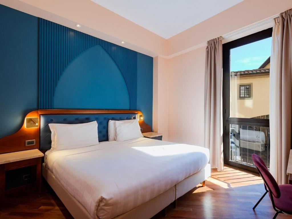 a bedroom with a bed and a large window at B&B Hotel Firenze Pitti Palace al Ponte Vecchio in Florence