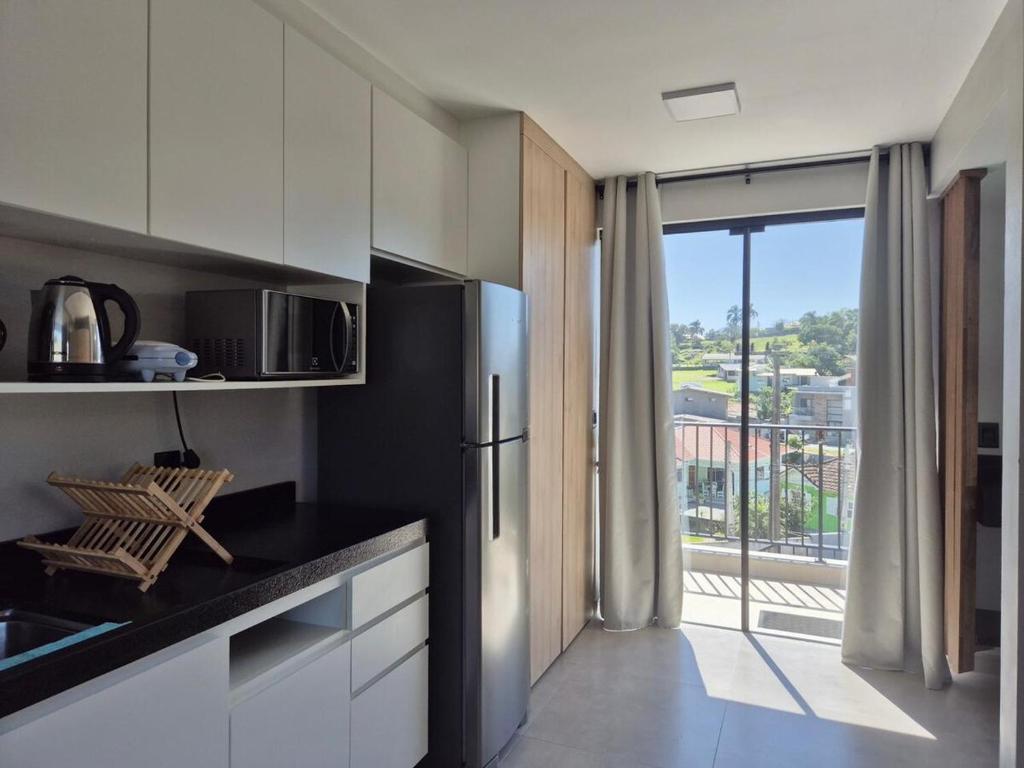 a kitchen with a refrigerator and a window with a view at VerdeMar Loft - Gamboa Beach - SC in Garopaba