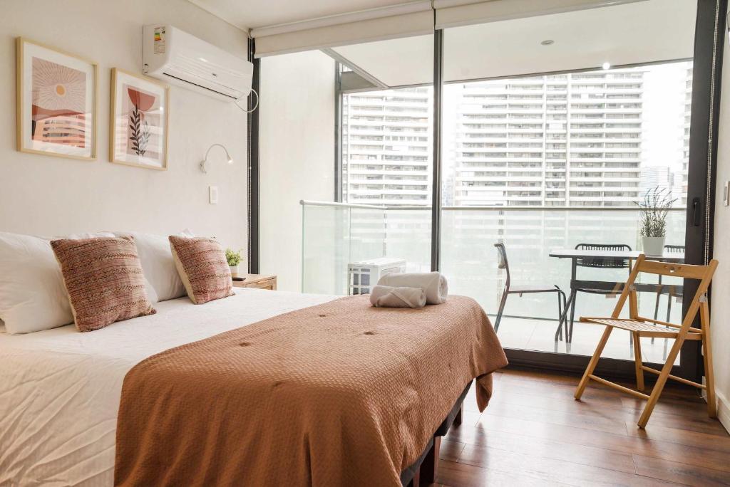 a bedroom with a bed with a table and a window at Luxury and Comfort in the Heart of Las Condes in Santiago