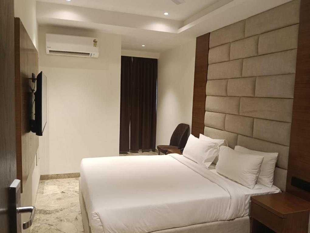 a bedroom with a large white bed and a chair at Silvotel Premier By Bizzgrow Hotels in Indore
