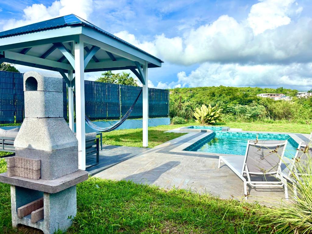 a swimming pool with a pavilion next to a swing and a swimming pool at Chez Valérie et Patrick in Le Diamant