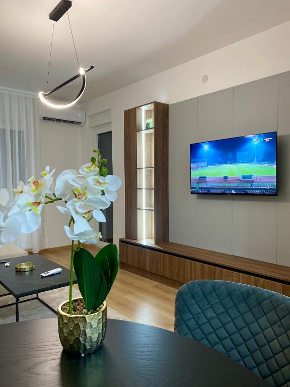 Una sala de estar con una mesa y un televisor en una pared. en FILIP Lux Apartman sa garažom, en Doboj