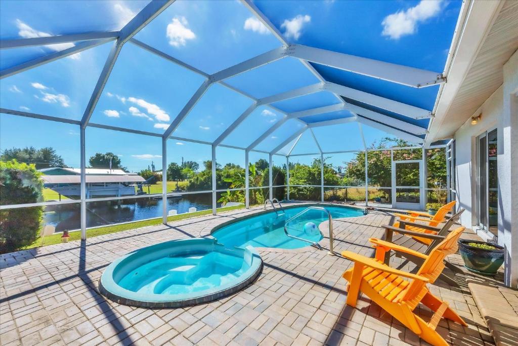 a swimming pool in a glass house with a patio and chairs at 27305 Voyageur in Punta Gorda