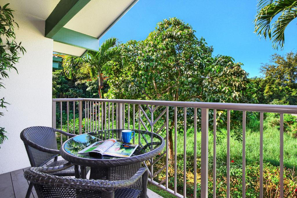 a table and chairs on a balcony with a book at Villas of Kamalii #35 in Princeville