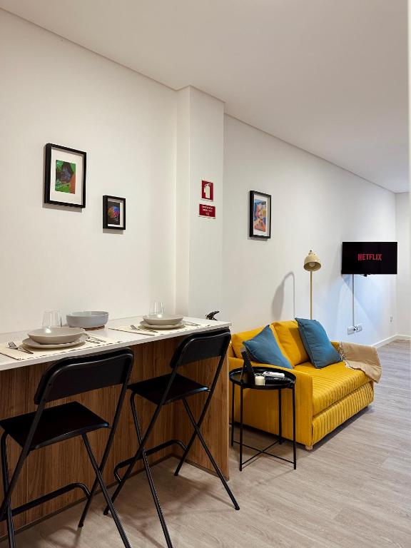 a living room with a yellow couch and a table at Color Avenida T0 in Águeda