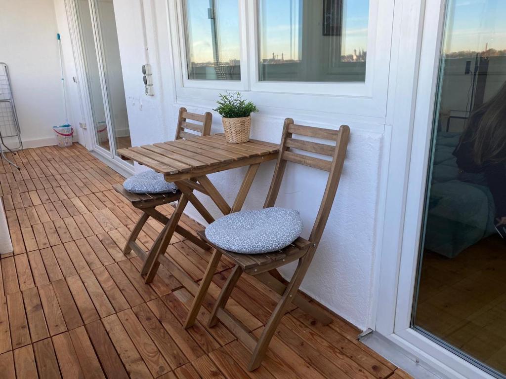 una mesa de madera y 2 sillas en el porche en LIBORIA I Über den Dächern Augsburgs, en Augsburg