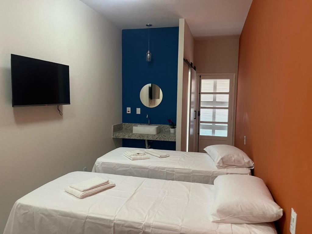 two beds in a room with a tv on the wall at Pousada Sete Colinas in Bragança Paulista