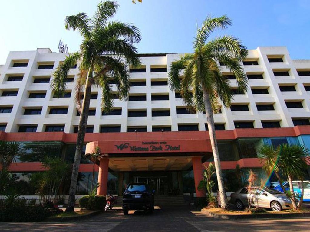 a large white building with palm trees in front of it at Wattana Park Hotel in Trang