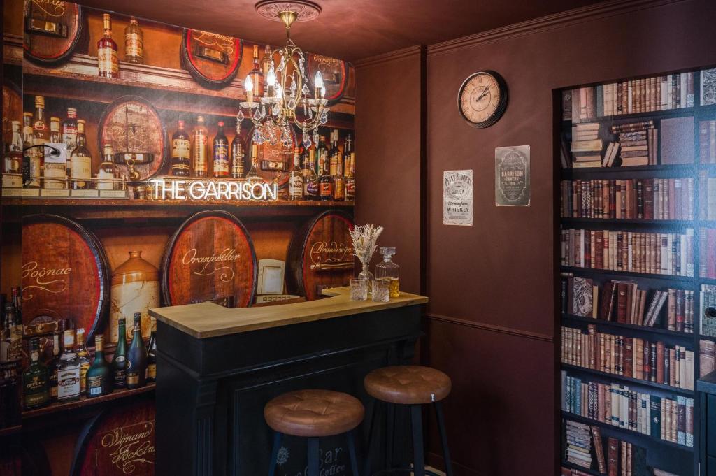 een bar met twee krukken en een plank met boeken bij Le Garrison - l'univers des Peaky Blinders à Bergerac in Bergerac