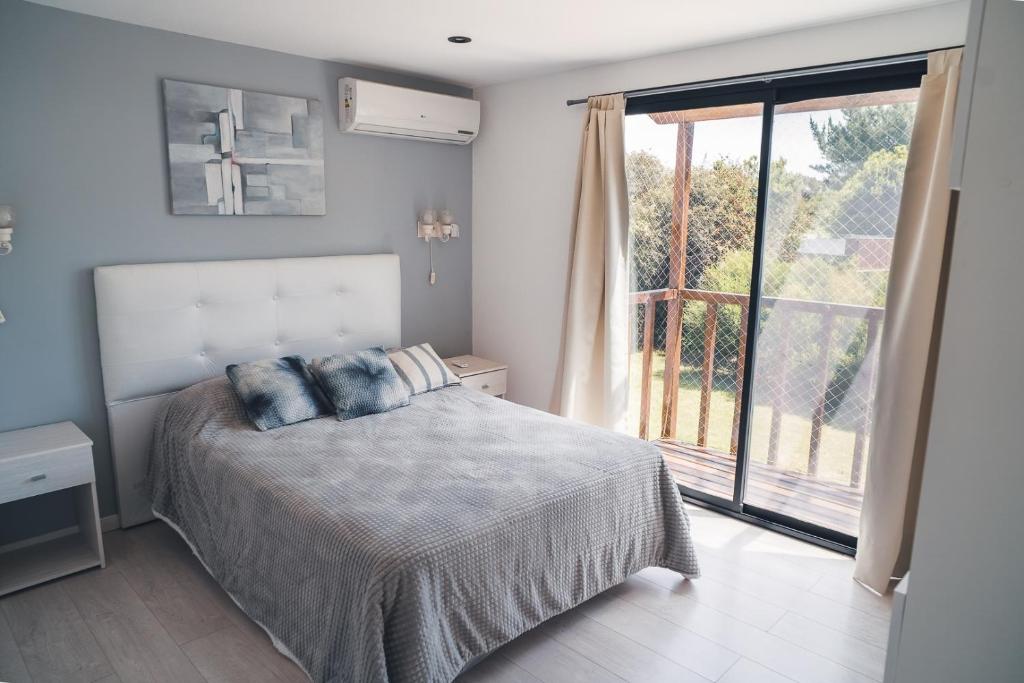 a bedroom with a bed and a large window at Check and home - Chapa II - 4 huéspedes con patio y parrilla in Chapadmalal