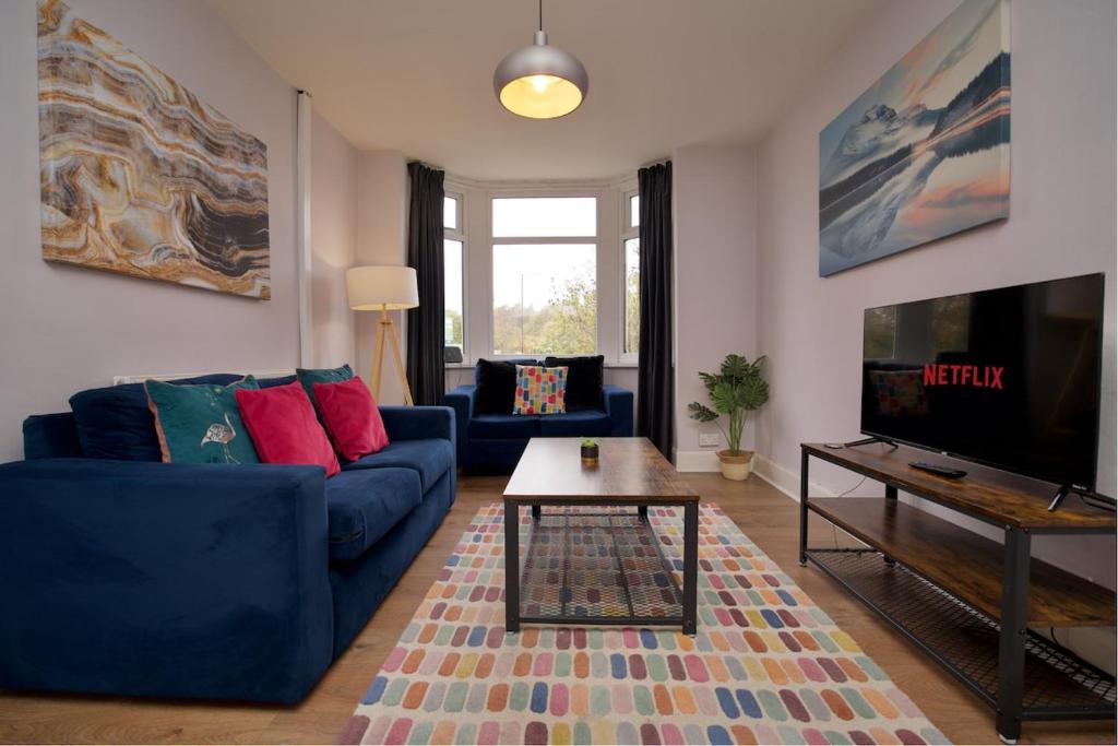 a living room with a blue couch and a tv at Whitley House - Stylish 3 Bedroom Home near Coventry City Centre in Coventry