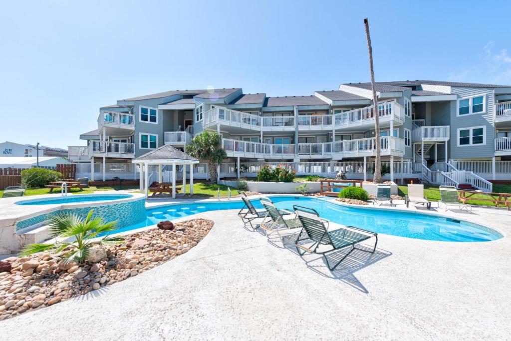 a large apartment building with a swimming pool and chairs at Beach Bum Headquarters in Mustang Beach
