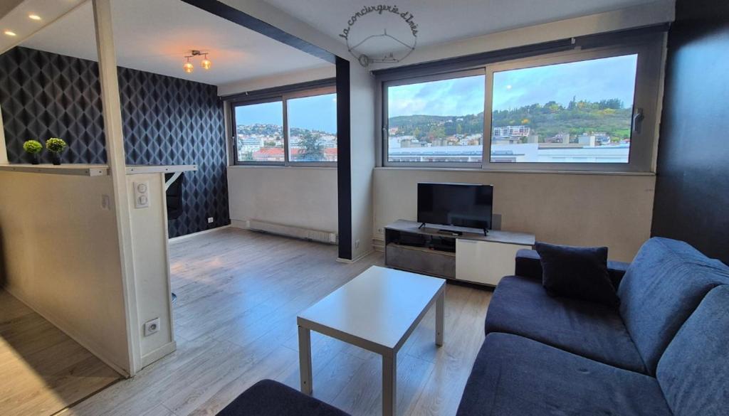 ein Wohnzimmer mit einer blauen Couch und einem Fernseher in der Unterkunft Le Berthelot #Parking in Clermont-Ferrand