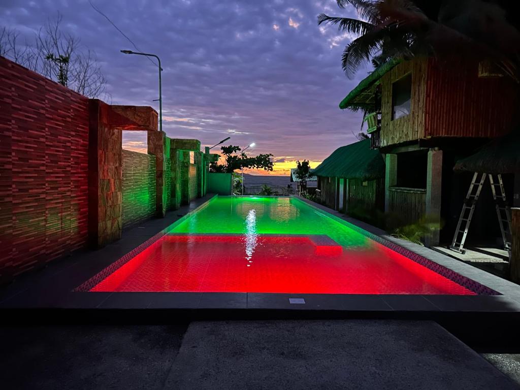 a swimming pool with red and green illumination at Beachfront Native house with pool in Nasugbu