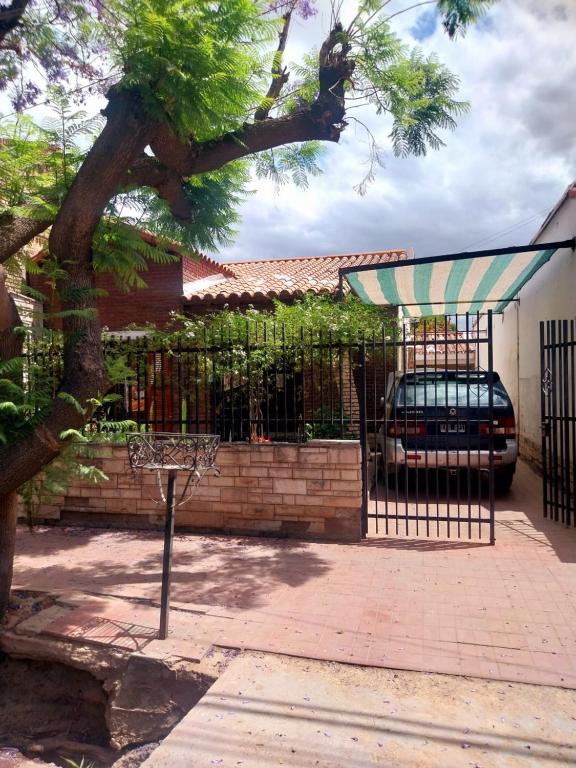a fence with a car parked in front of a house at La casa de las flores in Las Heras