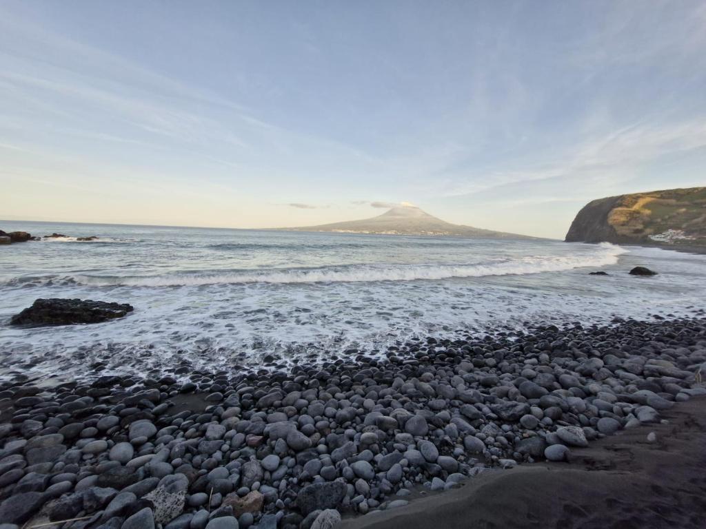 a rocky beach with a mountain in the background at Alma Atlântica - Pure Nature & Beach in Praia do Almoxarife