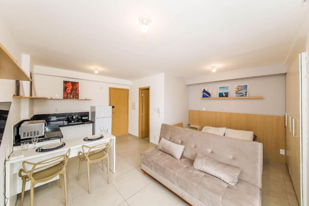 Una cocina y una sala de estar con un sofá y una mesa. en Studio Vibe 2206 com Piscina Academia e Varanda, en Juiz de Fora
