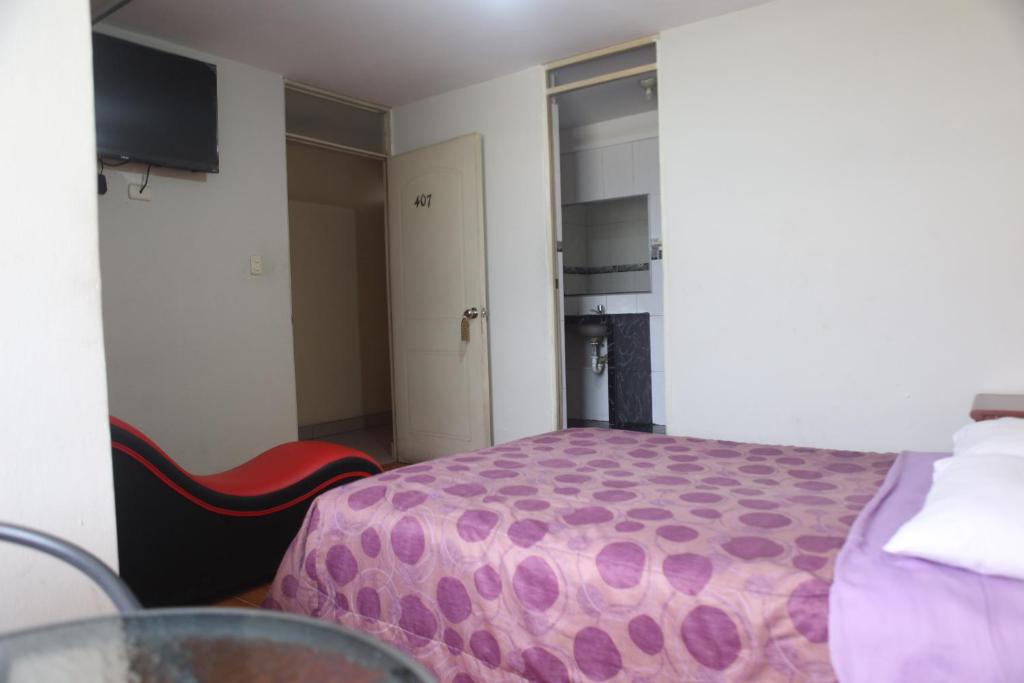 een kamer met een bed, een tafel en een deur bij Hostal Real in Lima