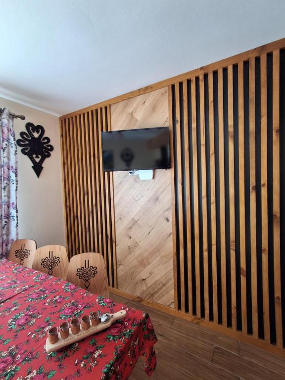 a dining room with a table and a television on a wall at Domki nad Borem in Male Ciche