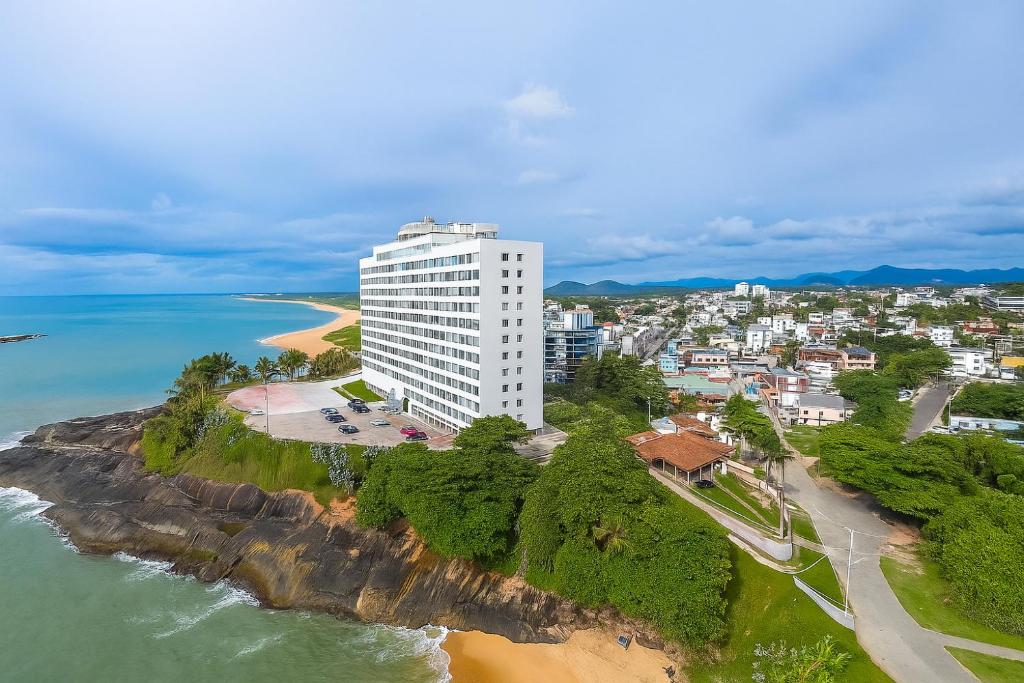 - une vue aérienne sur un bâtiment blanc à côté d'une plage dans l'établissement Apartamento de Frente pro Mar com Vista Incrível - 10 min da Praia do Morro, à Guarapari