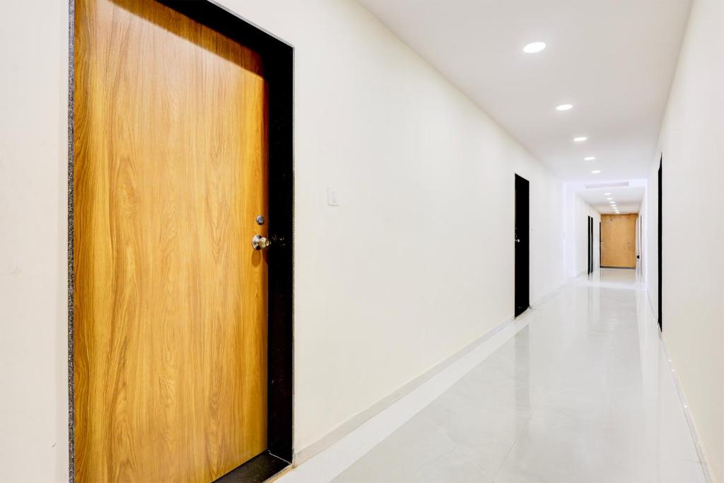 einen Flur mit Holztür und weißen Wänden in der Unterkunft Hotel O RamdevGarh Resort in Ahmedabad