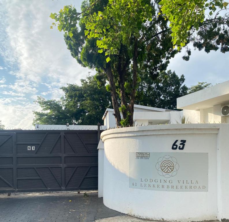 a building with a black gate and a tree at 63 Lodging Villa in Rustenburg