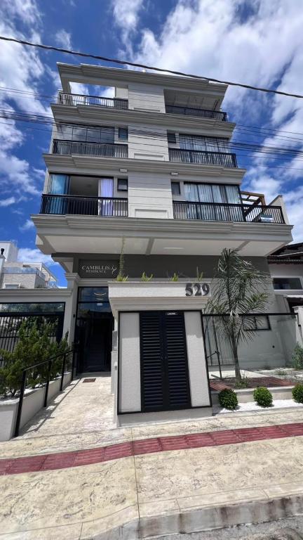 een hoog wit gebouw met een deur ervoor bij Cambllis in Bombinhas