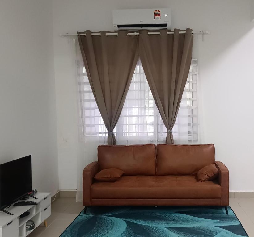 a living room with a brown couch in front of a window at Halia Homestay in Batu Pahat